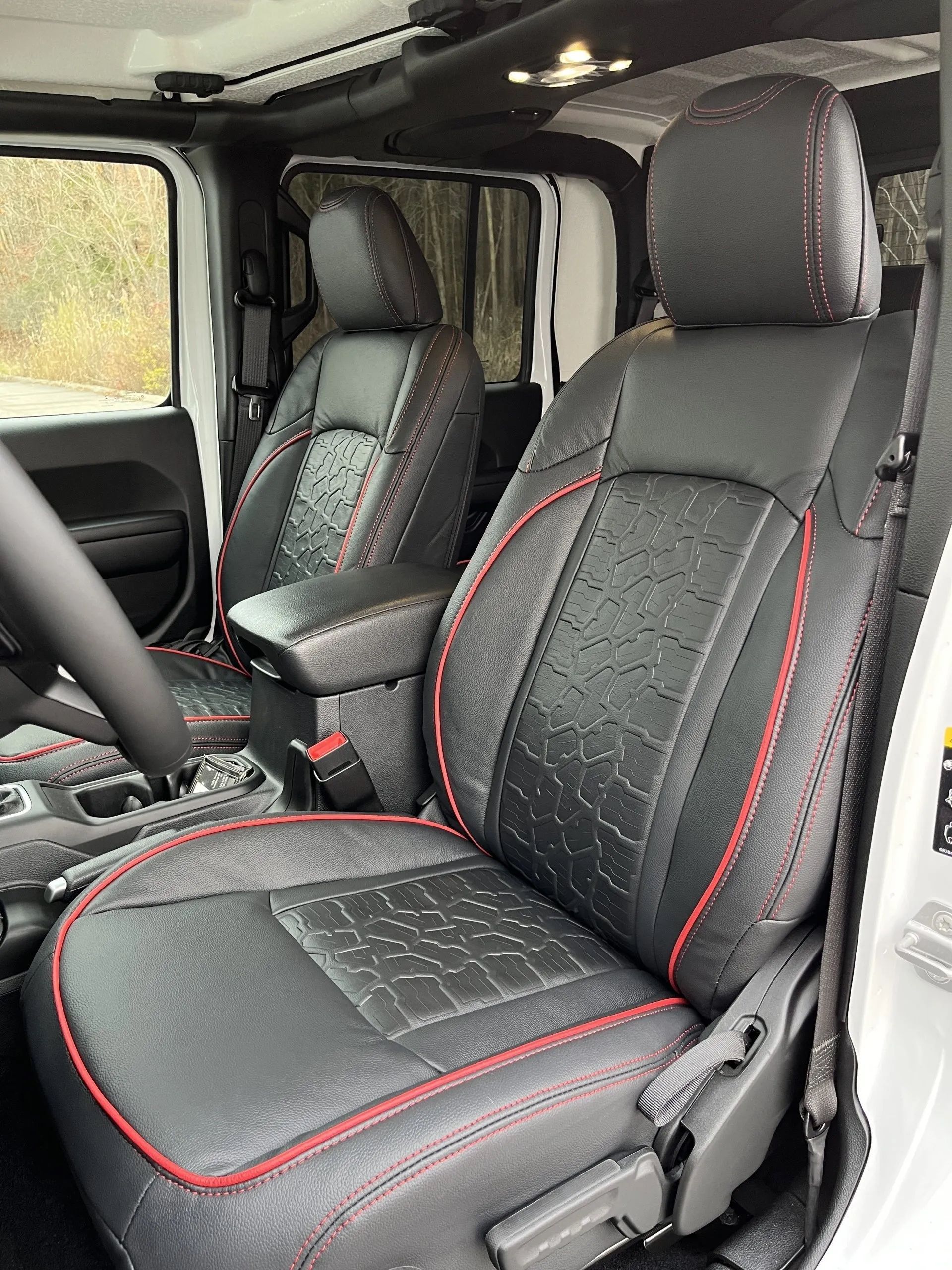 The interior of a white jeep wrangler with black and red seat covers