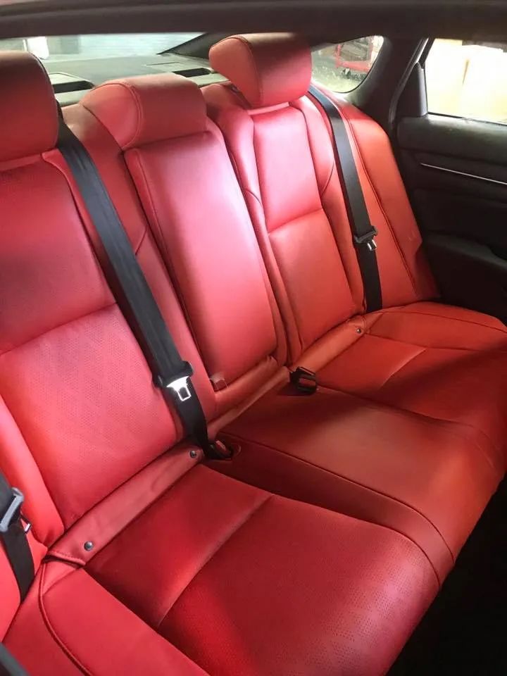 The back seat of a red honda accord with black seat belts