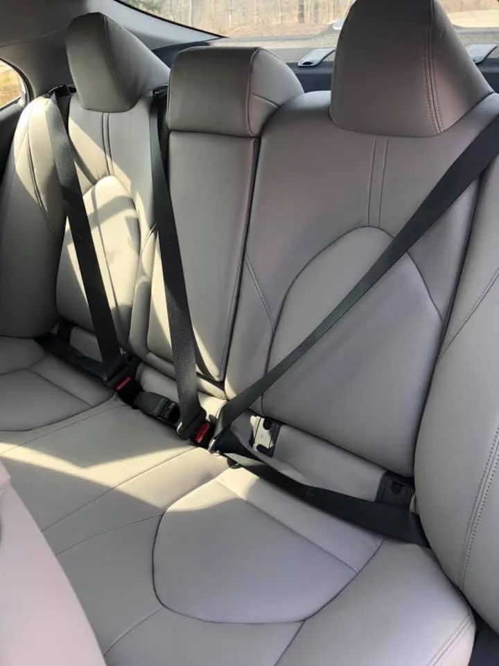 The back seat of a car with seat belts on it.