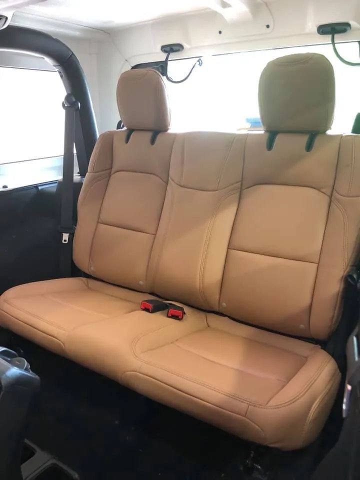 The back seat of a jeep wrangler with tan leather seats
