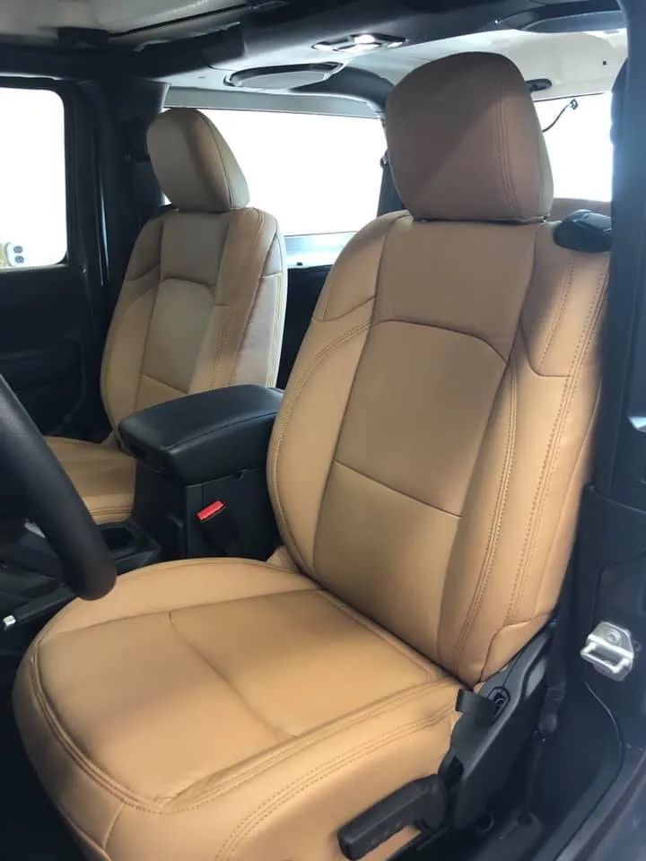 The front seats of a jeep wrangler are tan leather