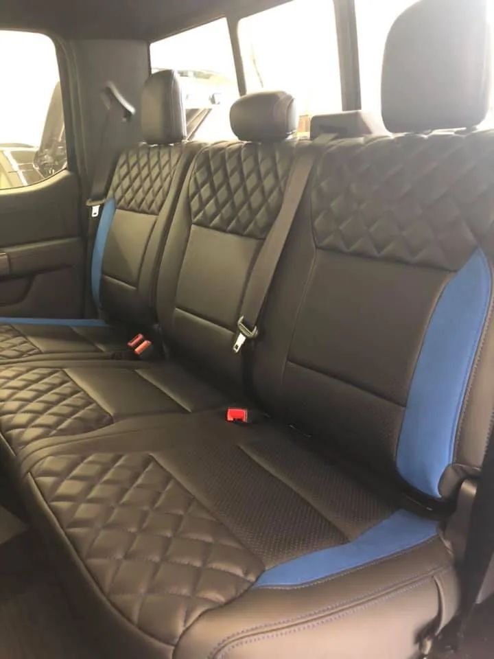 The back seat of a truck with black and blue seat covers