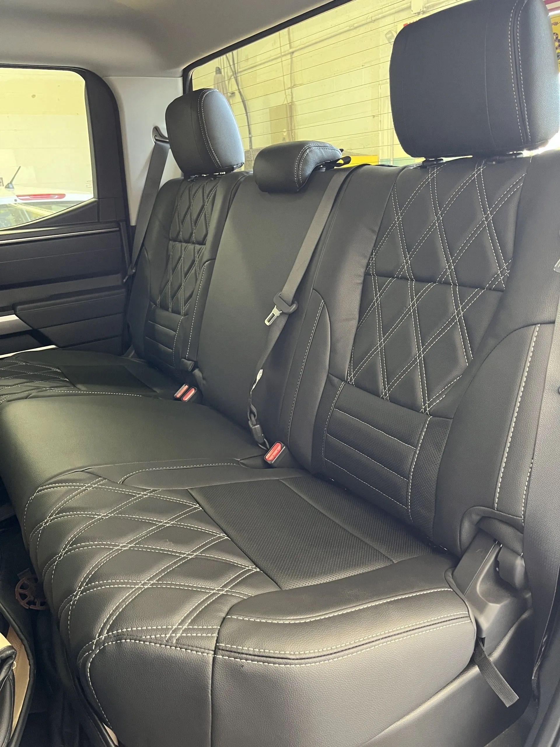 The back seat of a truck with black seat covers