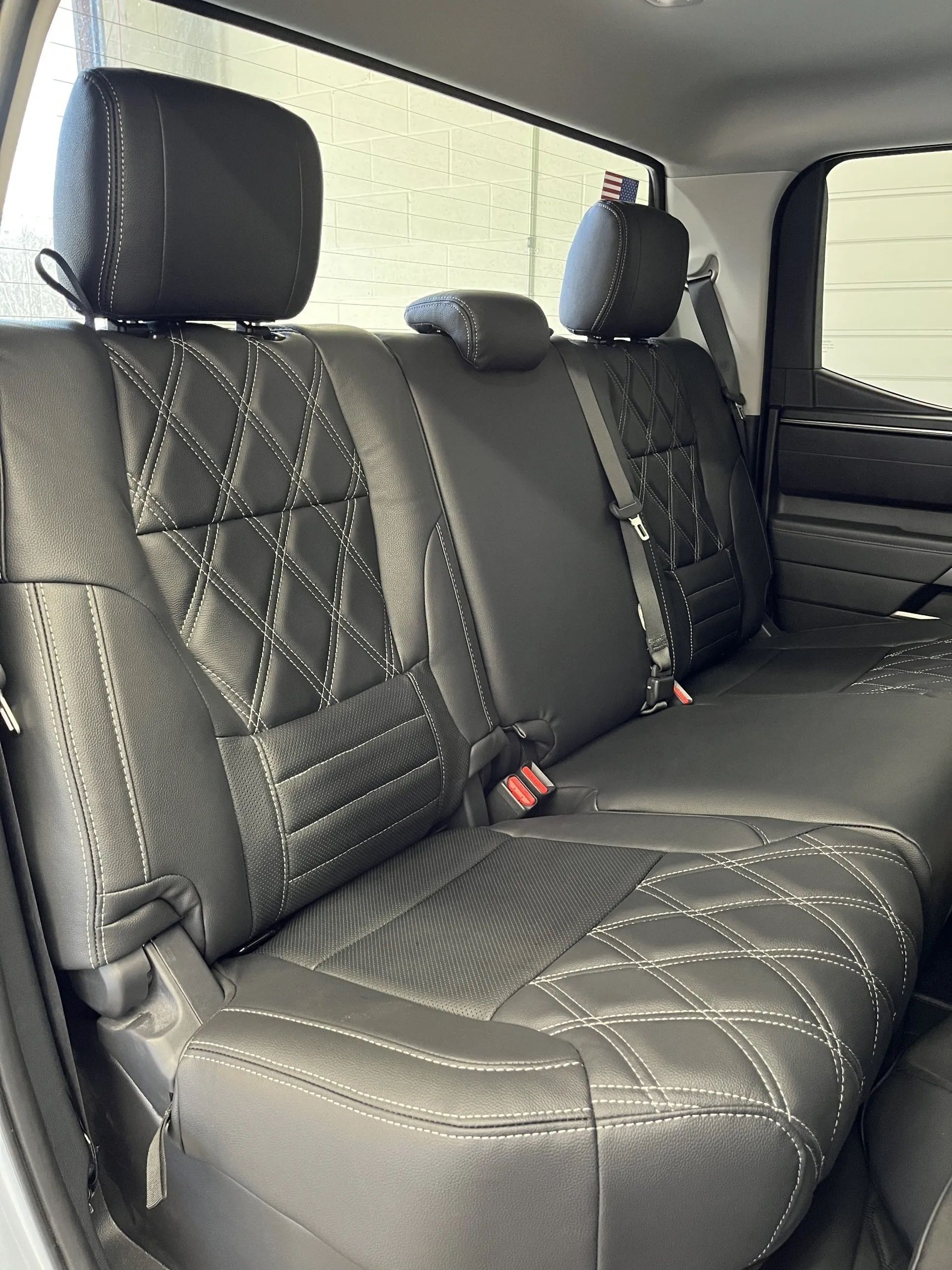 The back seat of a truck with black leather seat covers