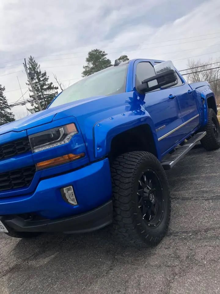 A blue truck is parked on the side of the road.