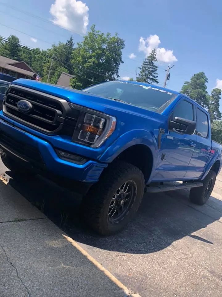 A blue ford f150 truck is parked in a parking lot