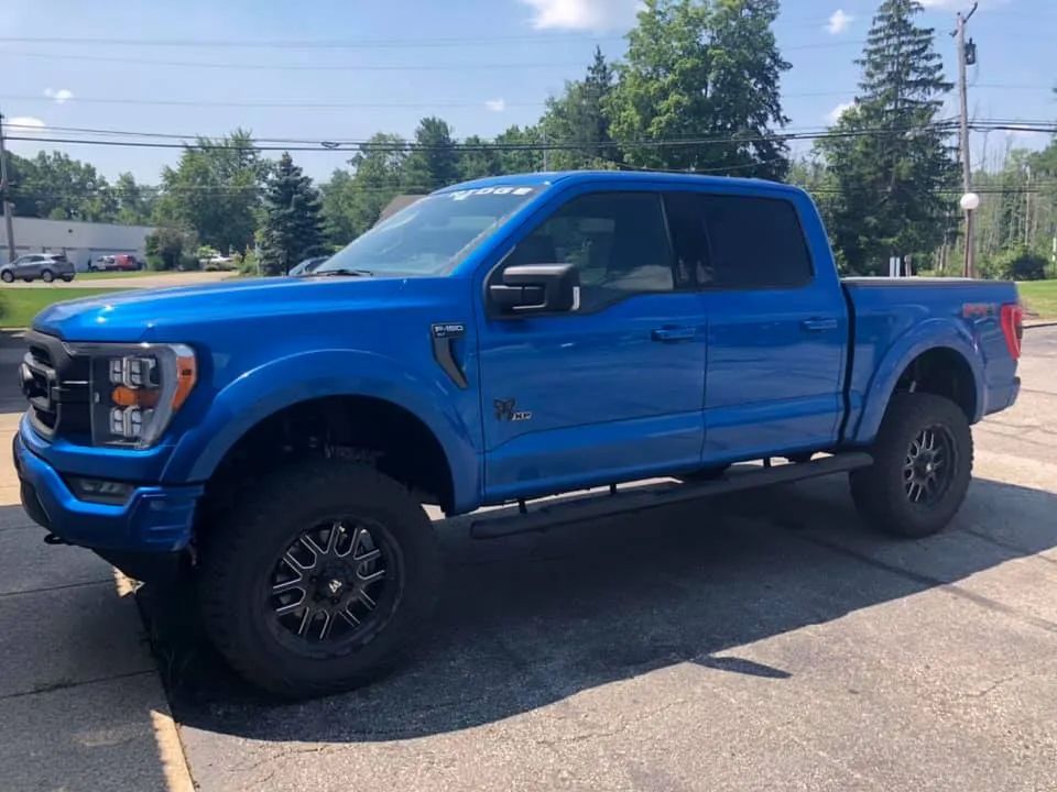 A blue ford f150 truck is parked in a parking lot