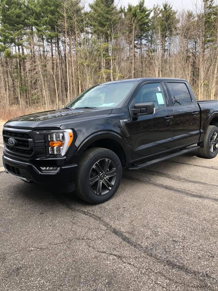 A black ford f150 truck is parked on the side of the road