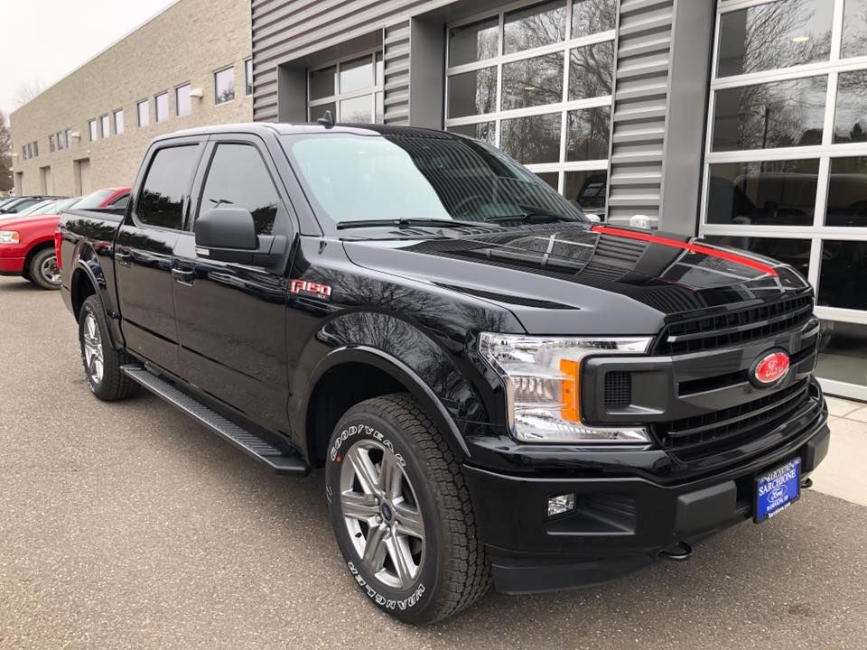 A black ford f150 truck is parked in front of a building