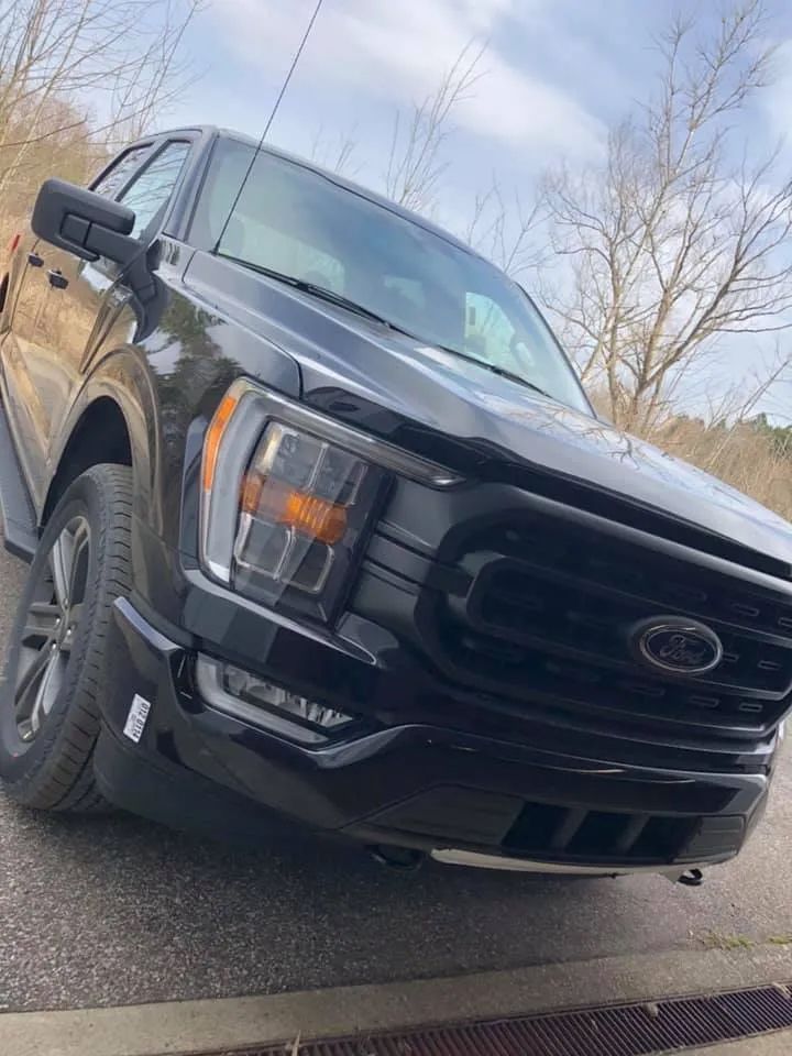 A black ford f150 truck is parked on the side of the road
