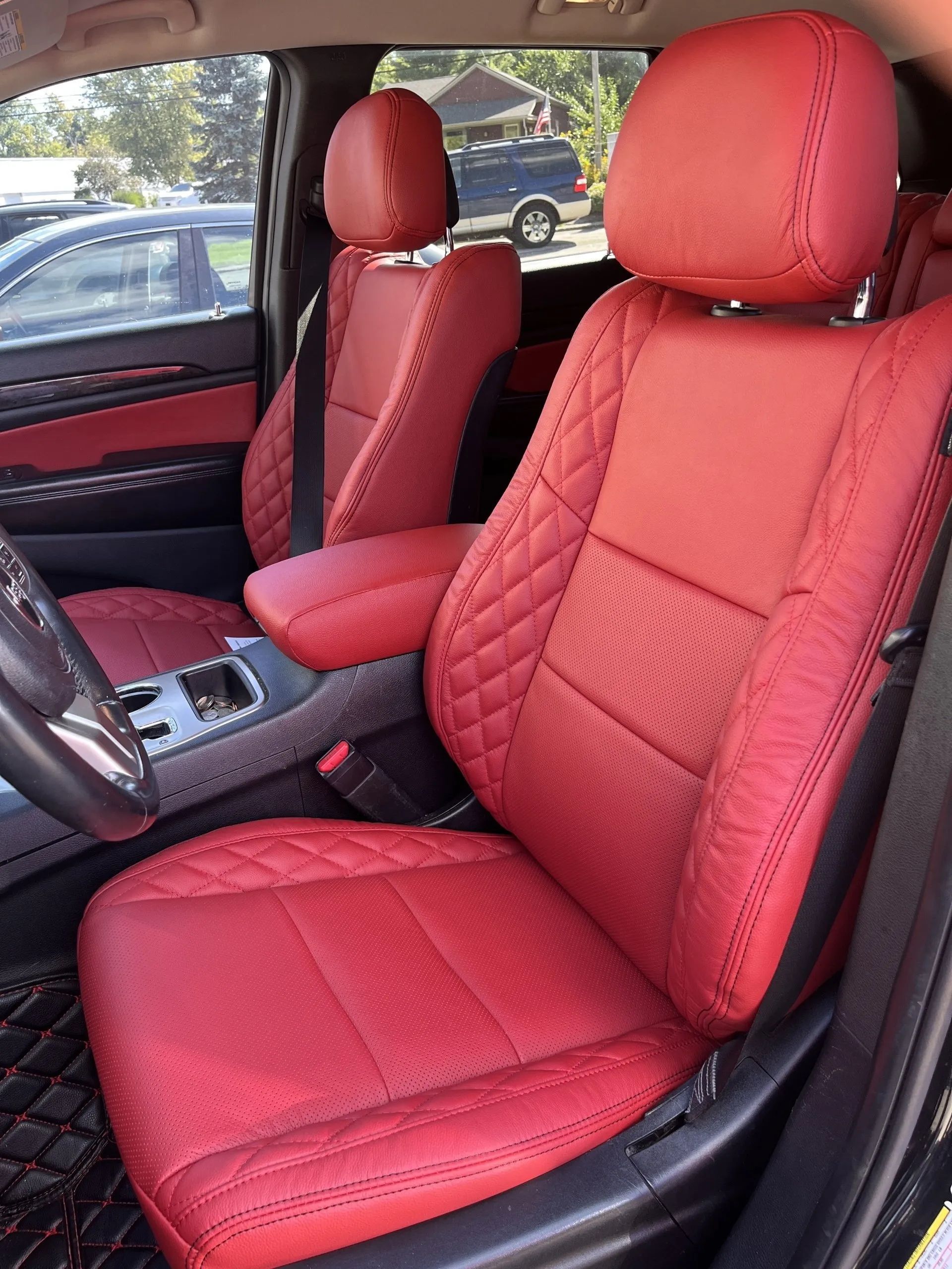 The front seats of a black car with red seat covers