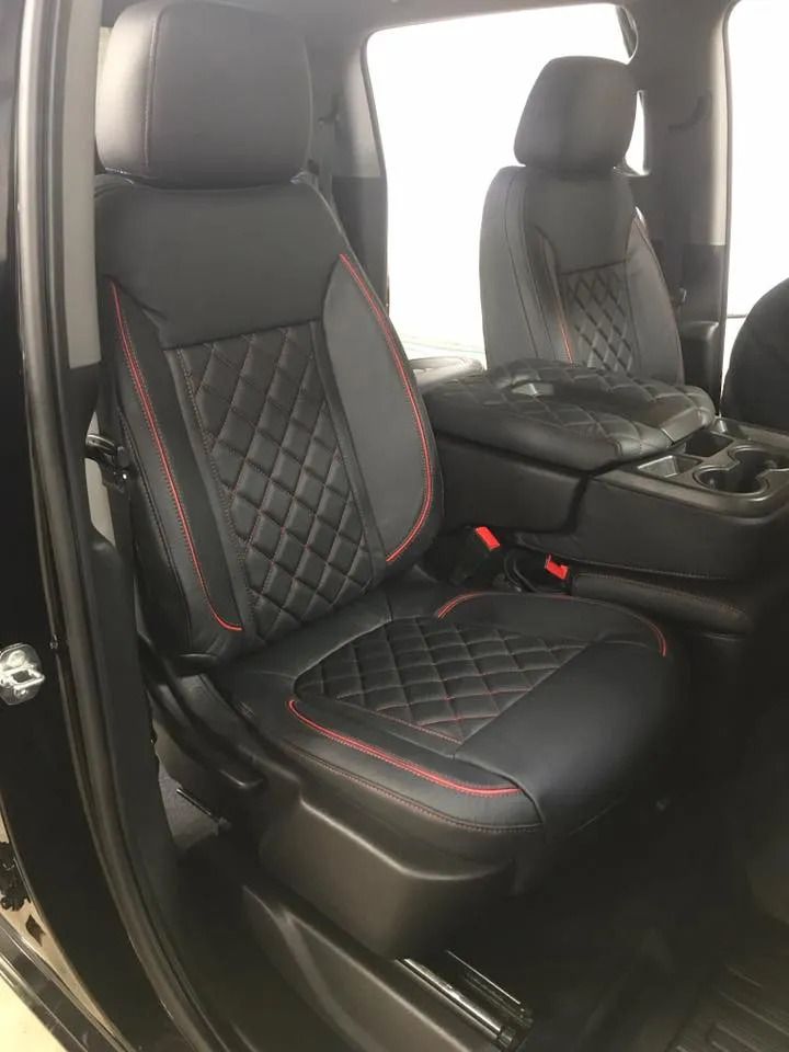 The interior of a black truck with black and red seat covers