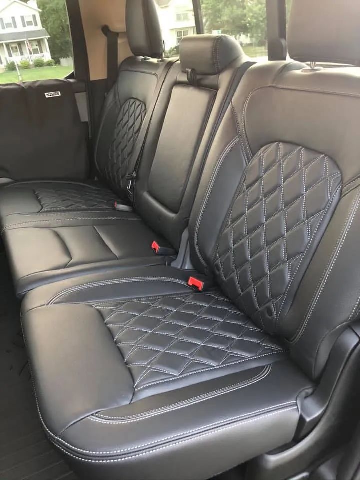 The back seat of a truck with black leather seat covers