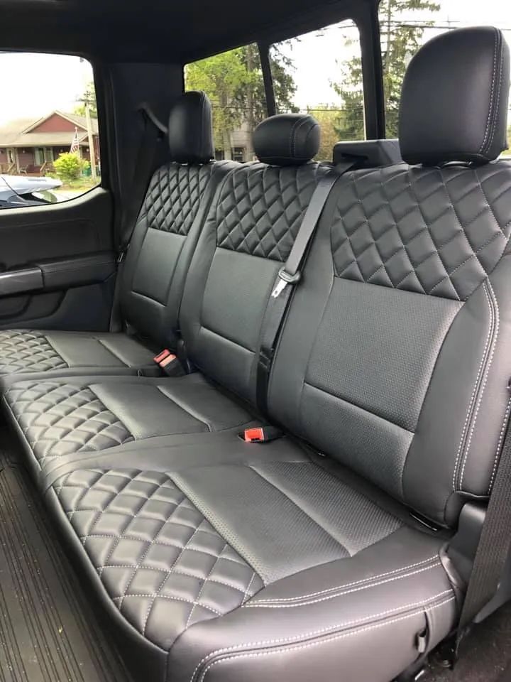 The back seat of a truck with black leather seat covers