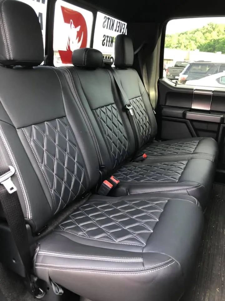 The back seat of a truck with black leather seat covers