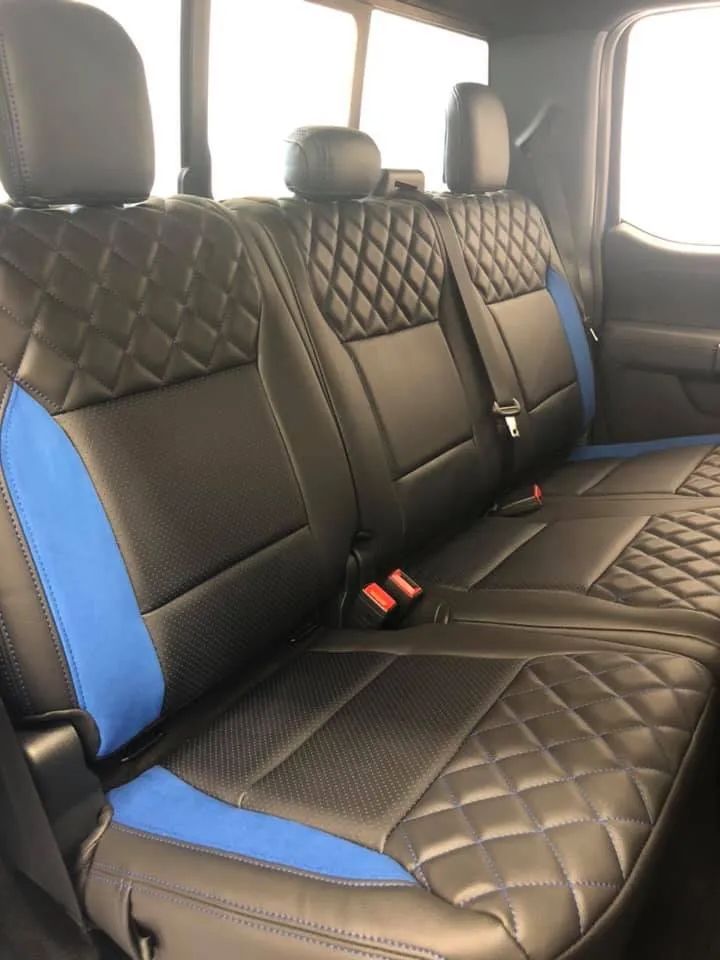 The back seat of a truck with black and blue seat covers