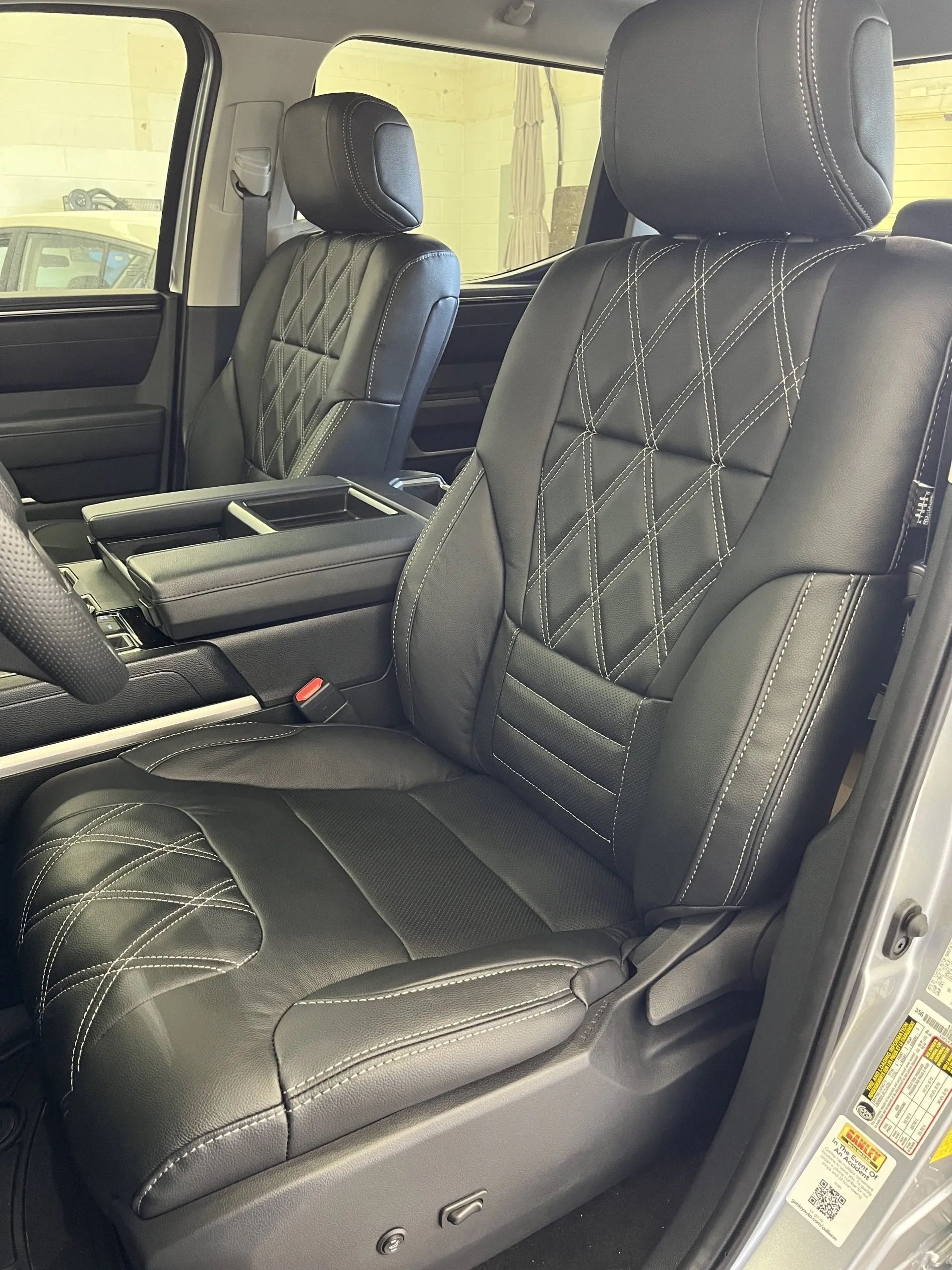 The front seats of a silver toyota tundra with black leather seat covers