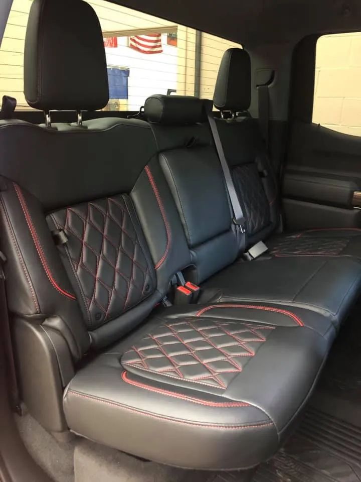 The back seat of a truck with black and red seat covers