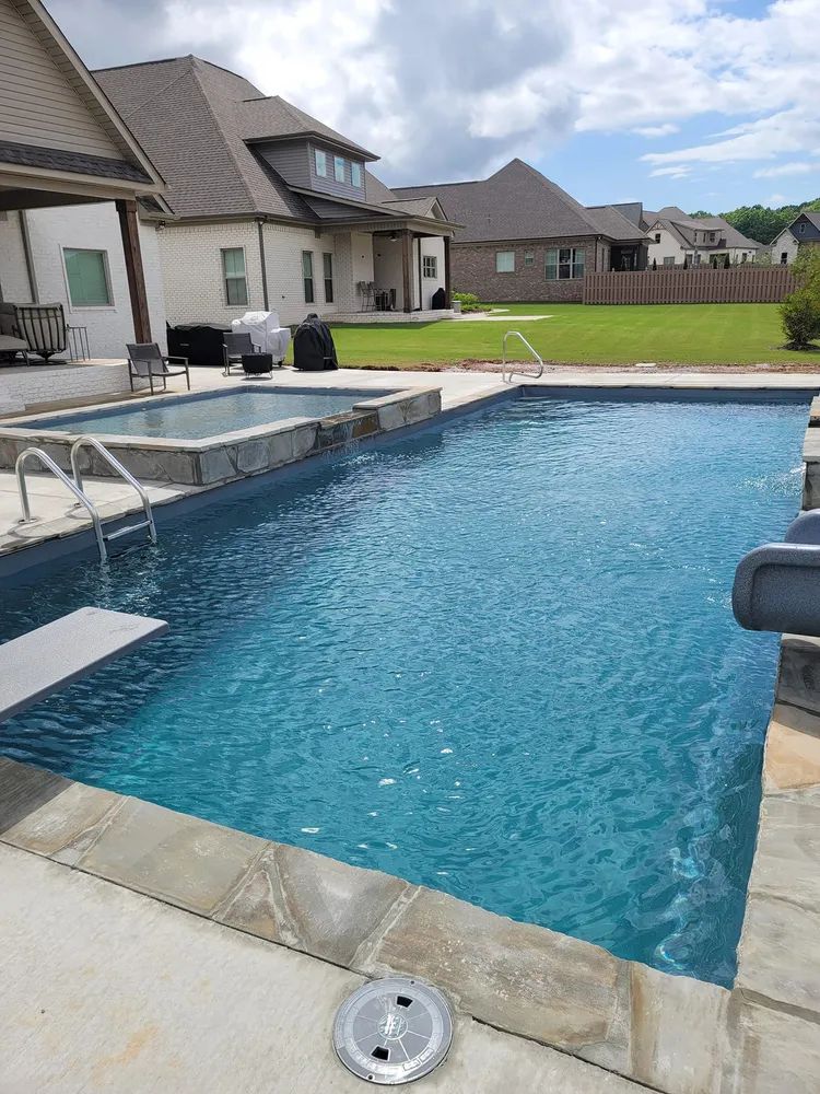 Backyard swimming pool with patio and suburban houses in the background