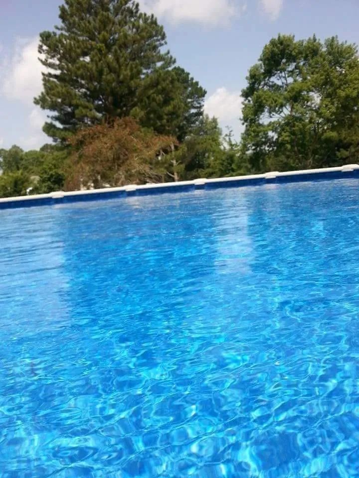Blue swimming pool with rippling water and trees in the background