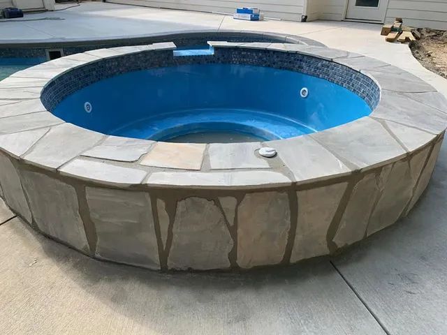 Round above-ground pool with blue interior and tan stone-pattern exterior on a concrete patio