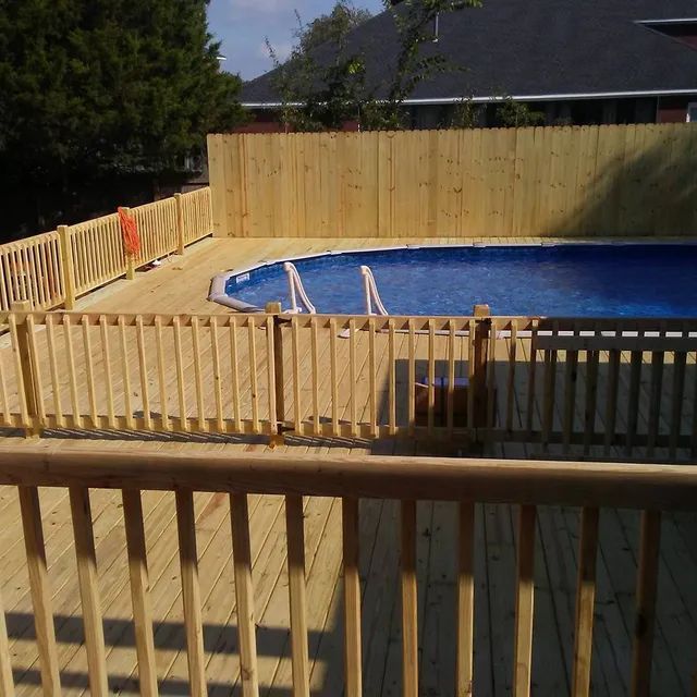 Backyard deck with a fenced swimming pool and wooden privacy fence in sunlight