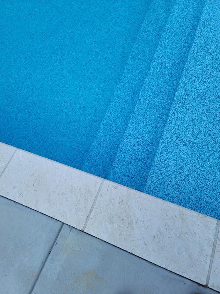 Blue textured surface with diagonal shadows above a light stone or concrete edge