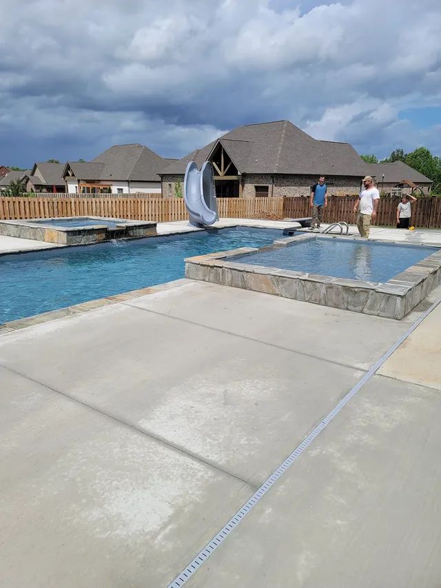 Outdoor pool with a water slide and people by the deck at a resort.