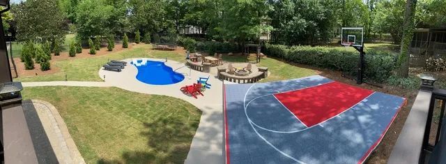 Outdoor playground with blue and red play areas, sandbox, benches, and trees nearby.