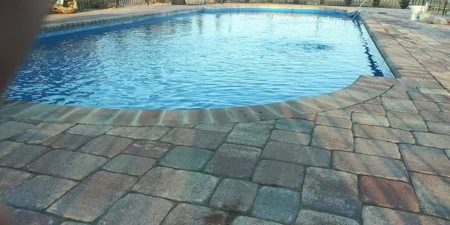 Blue swimming pool beside a stone patio on a sunny day