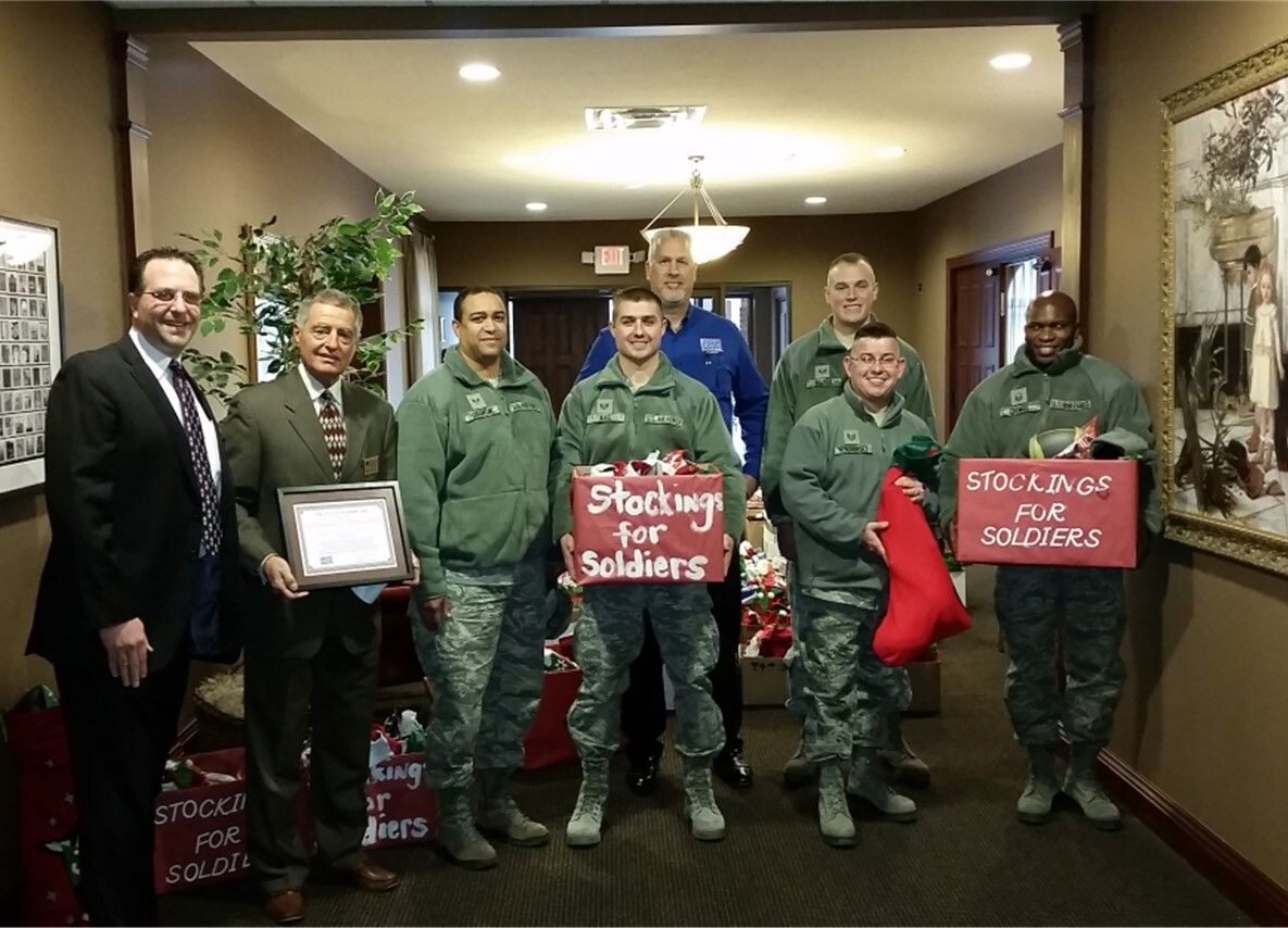 A group of men in military uniforms holding signs that say stockings for soldiers