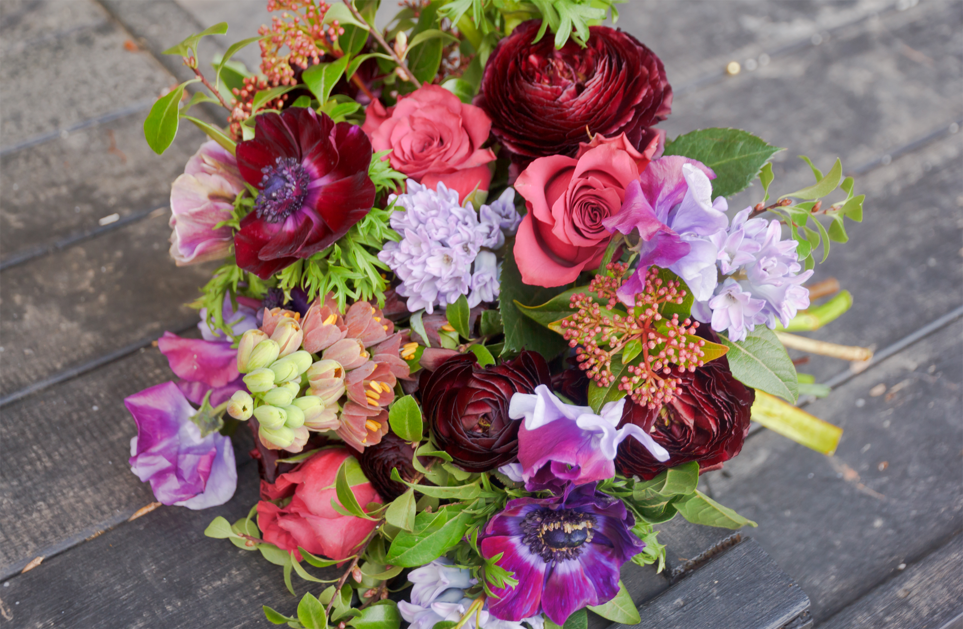 a bouquet of flowers including red roses and purple anemones