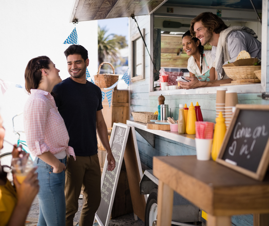 A group of people are standing in front of a food truck.