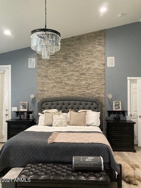 A bedroom with a large bed and a chandelier hanging from the ceiling.