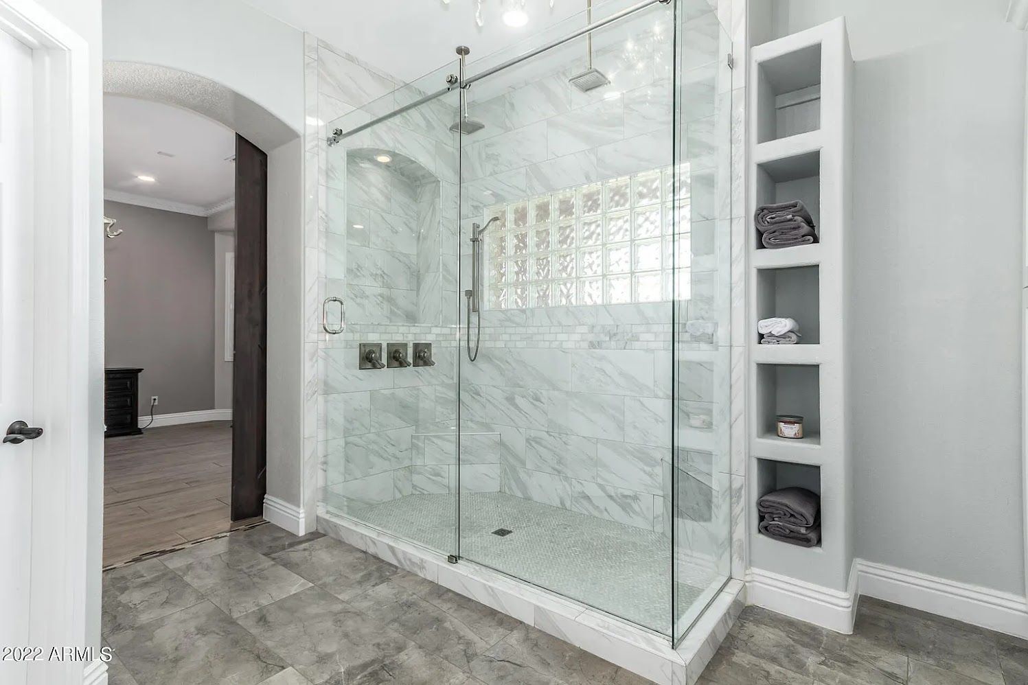 A bathroom with a large walk in shower with sliding glass doors.