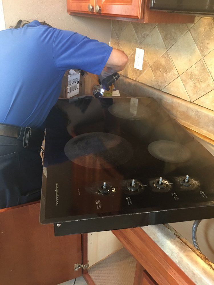 A man is working on a stove top oven in a kitchen.