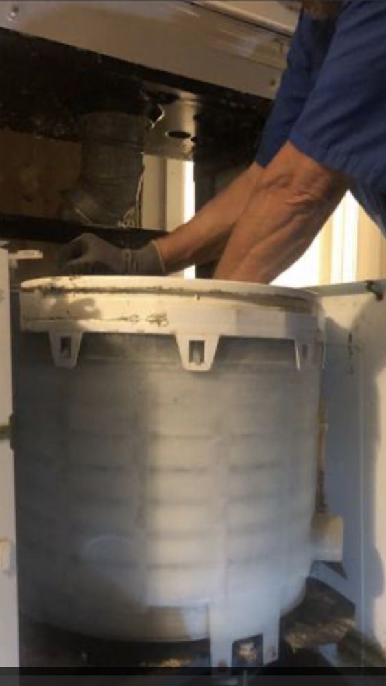 A man in a blue shirt is working on a washing machine.