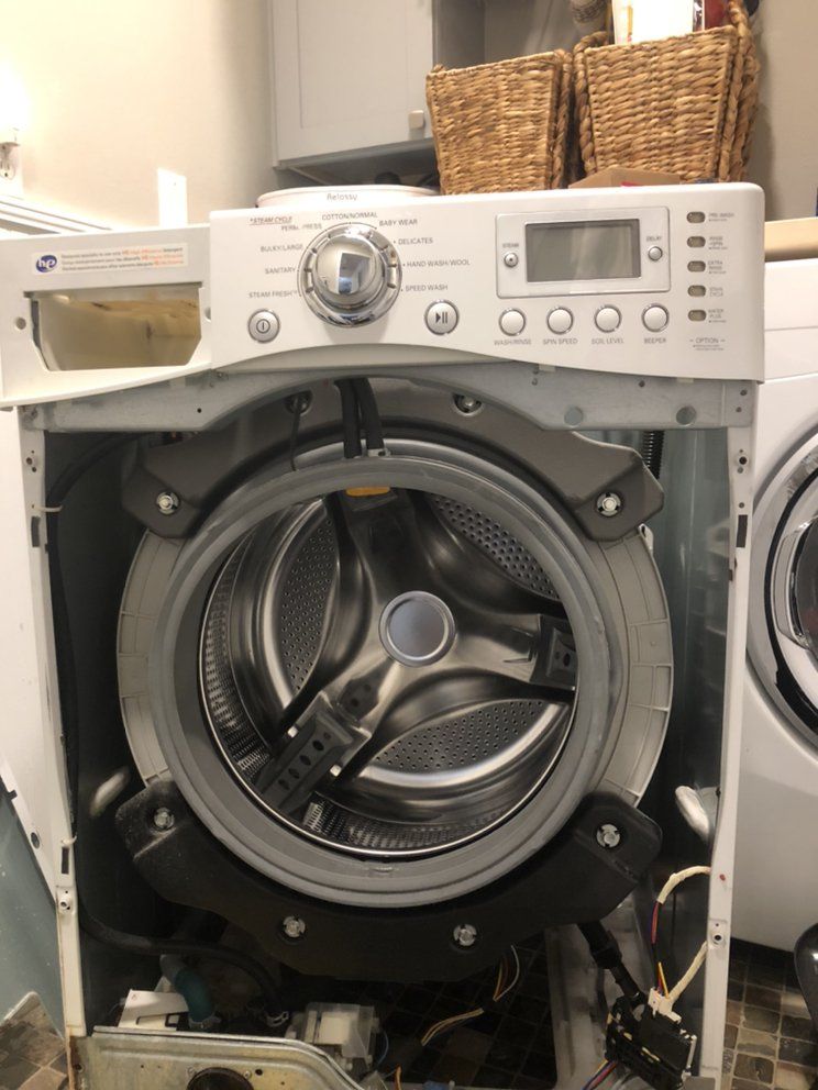 A washing machine is being repaired in a laundry room.