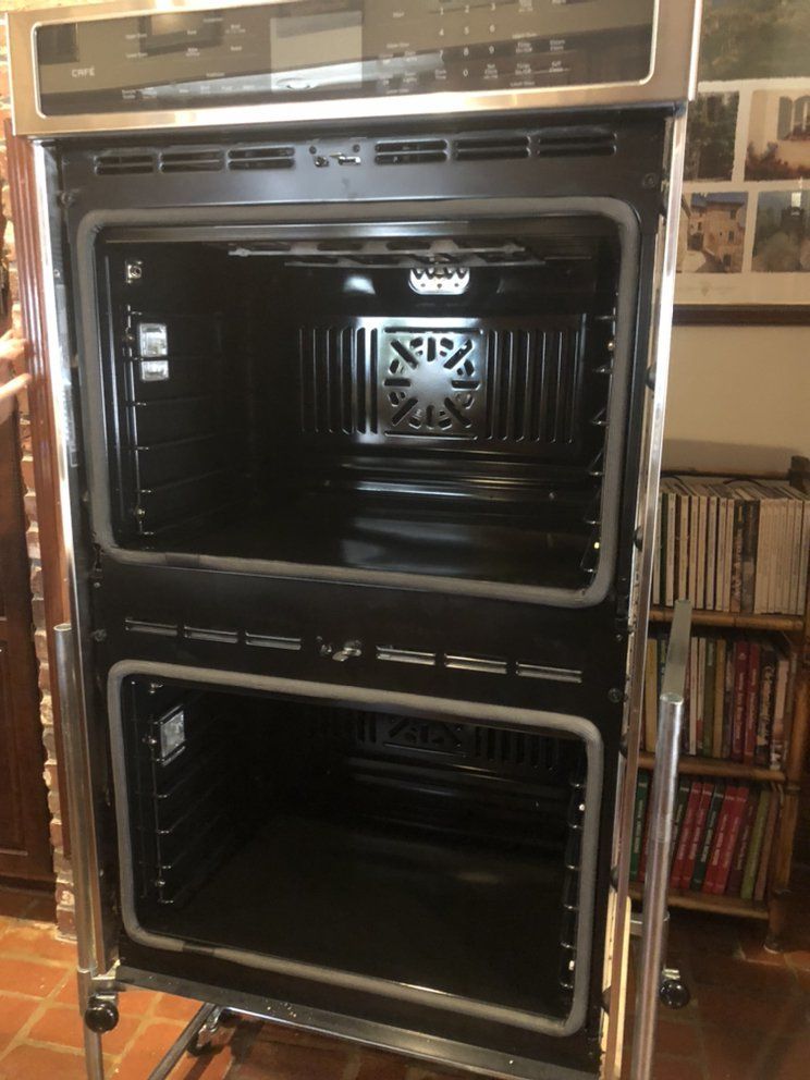 An empty double oven is sitting on a stand in a kitchen.