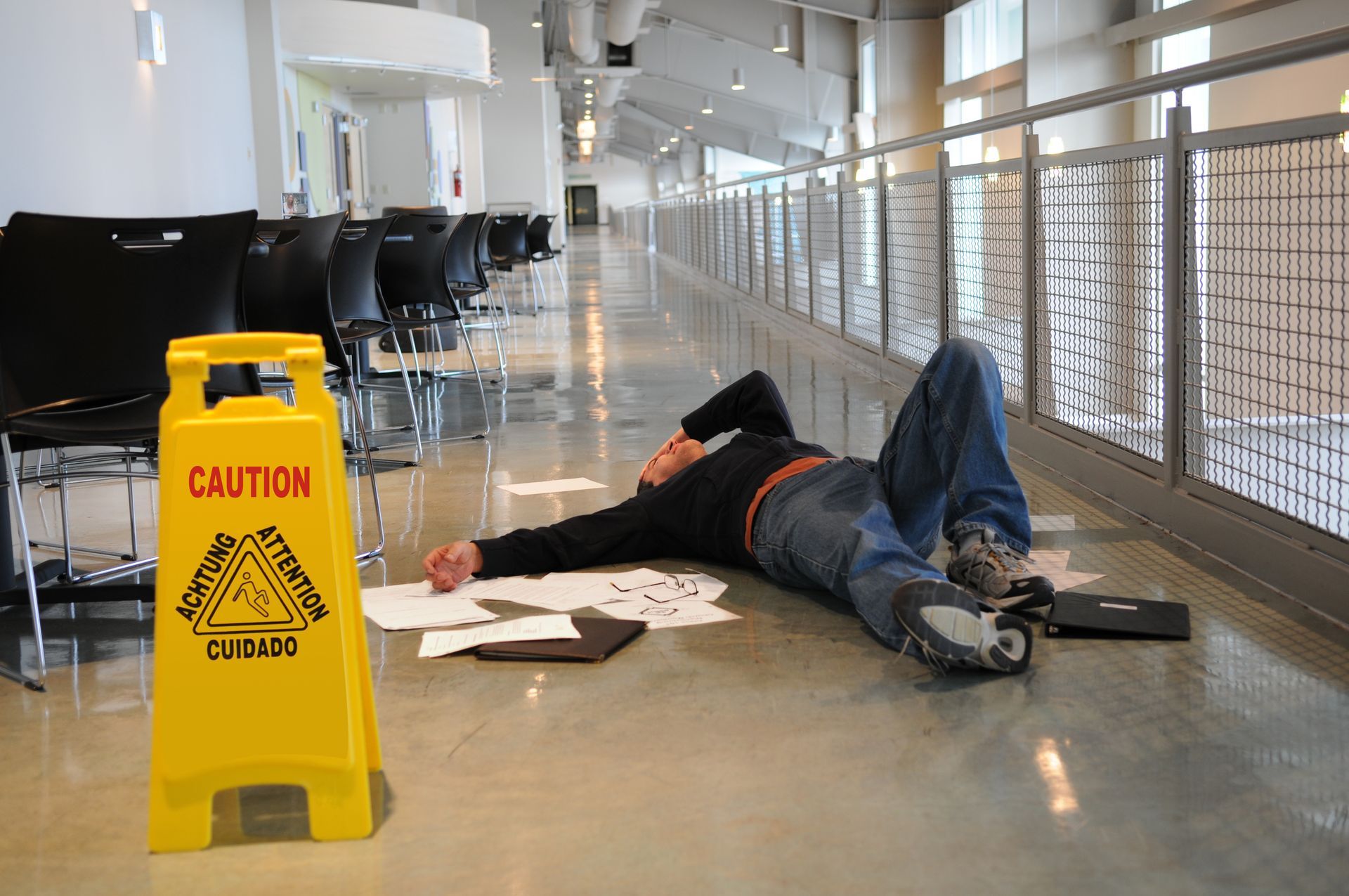 A man is laying on the floor next to a caution sign.