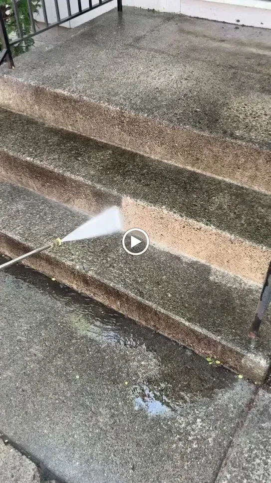 Pressure washing concrete steps; spray cleaning dirt and grime.