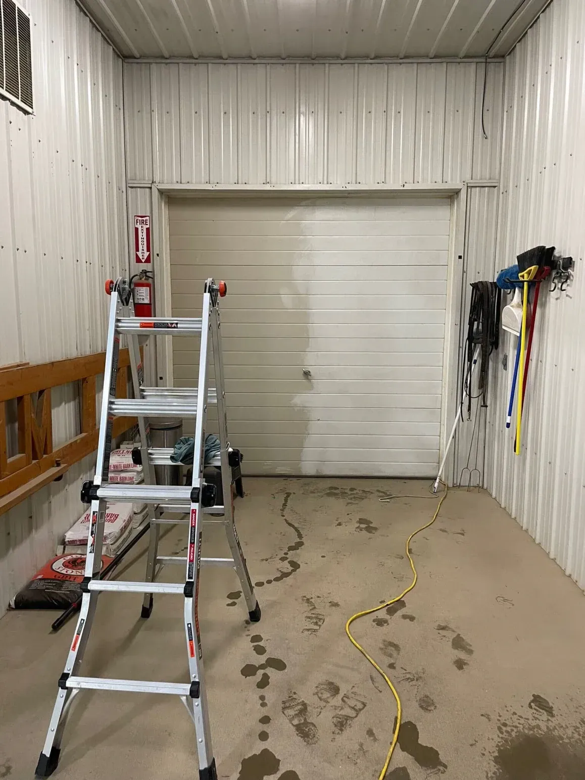 Interior of a garage with a closed garage door, ladder, and equipment.