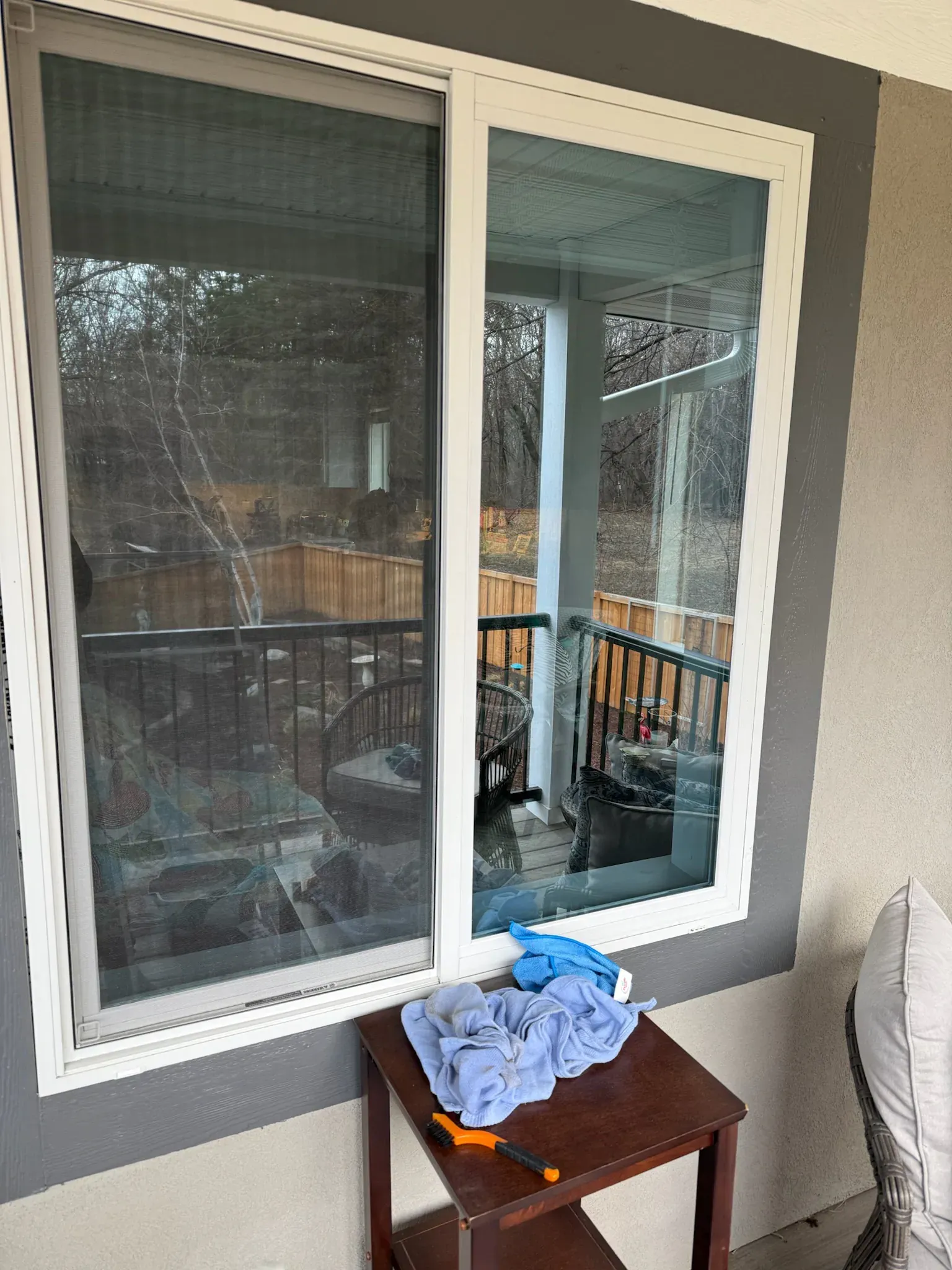 Sliding glass door with white frame. Table with tools and blue cloth. View of porch and backyard.