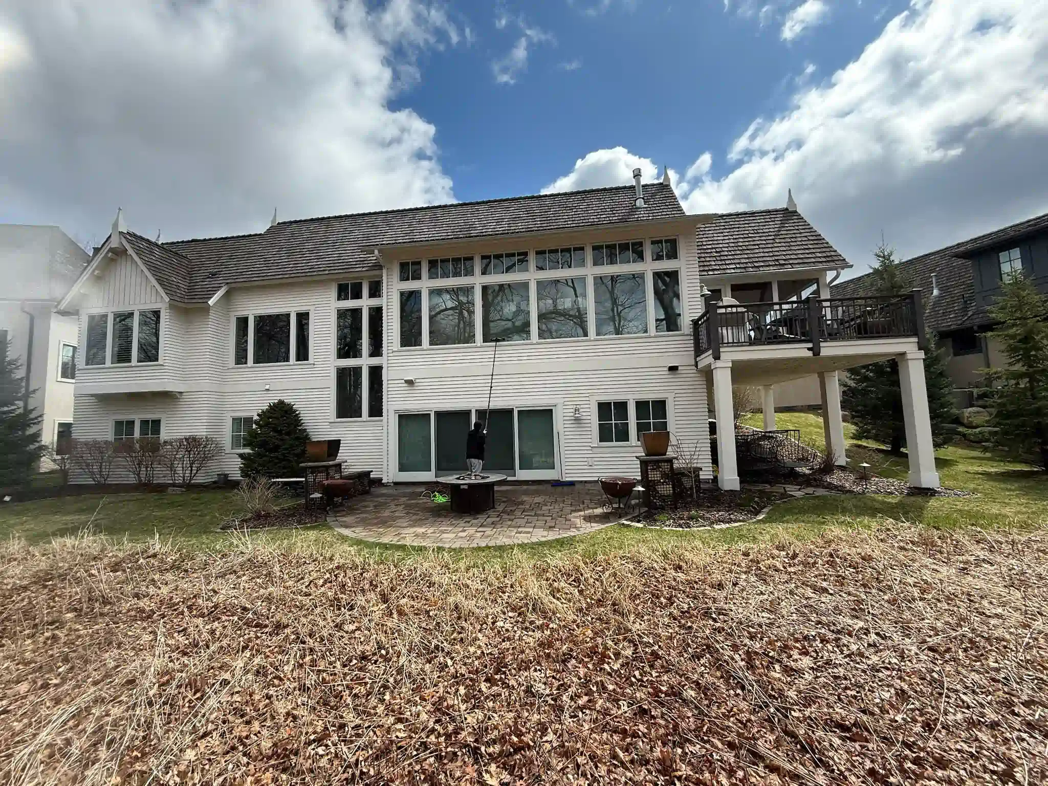 White house with large windows and a balcony, set against a cloudy blue sky.