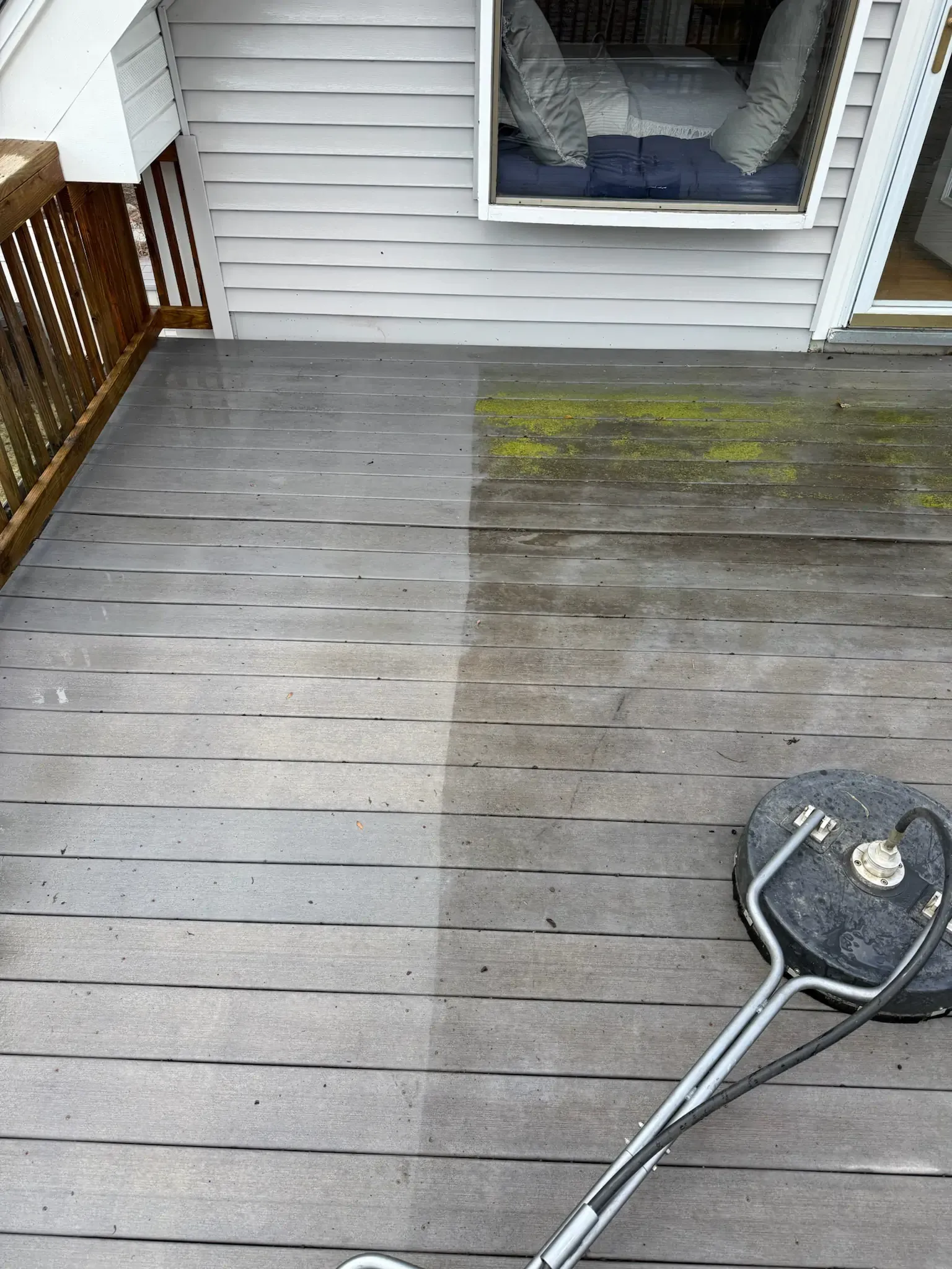Power washer cleaning a wooden deck, showing the before and after with green moss.