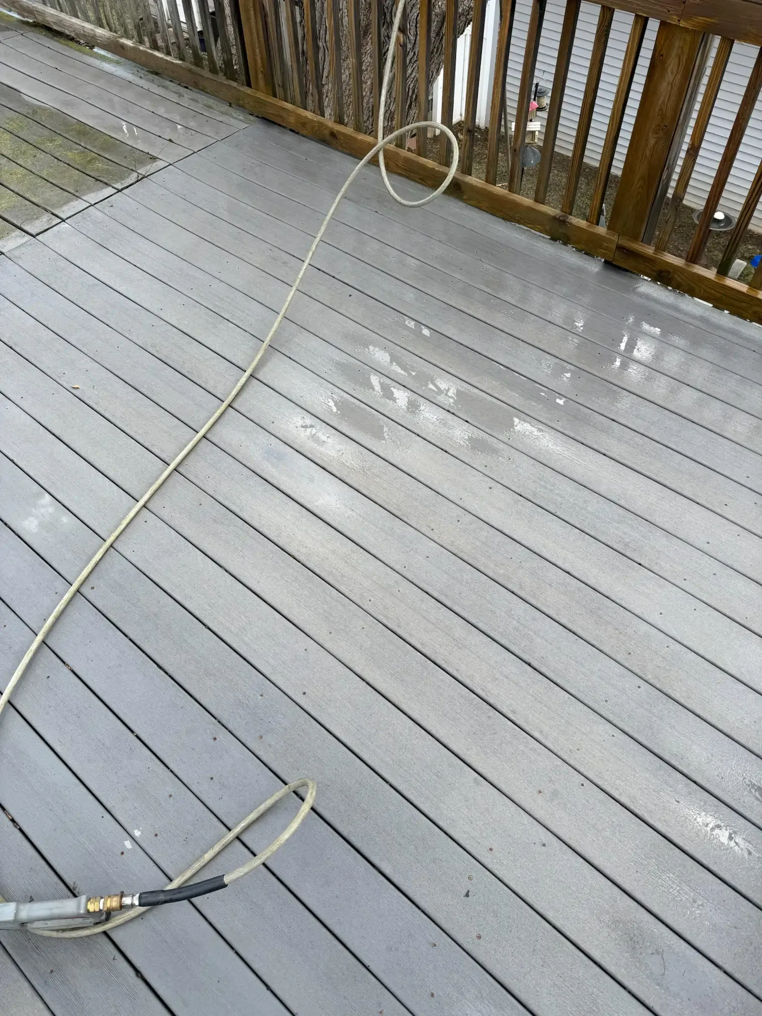 Wet, gray composite deck with a hose.