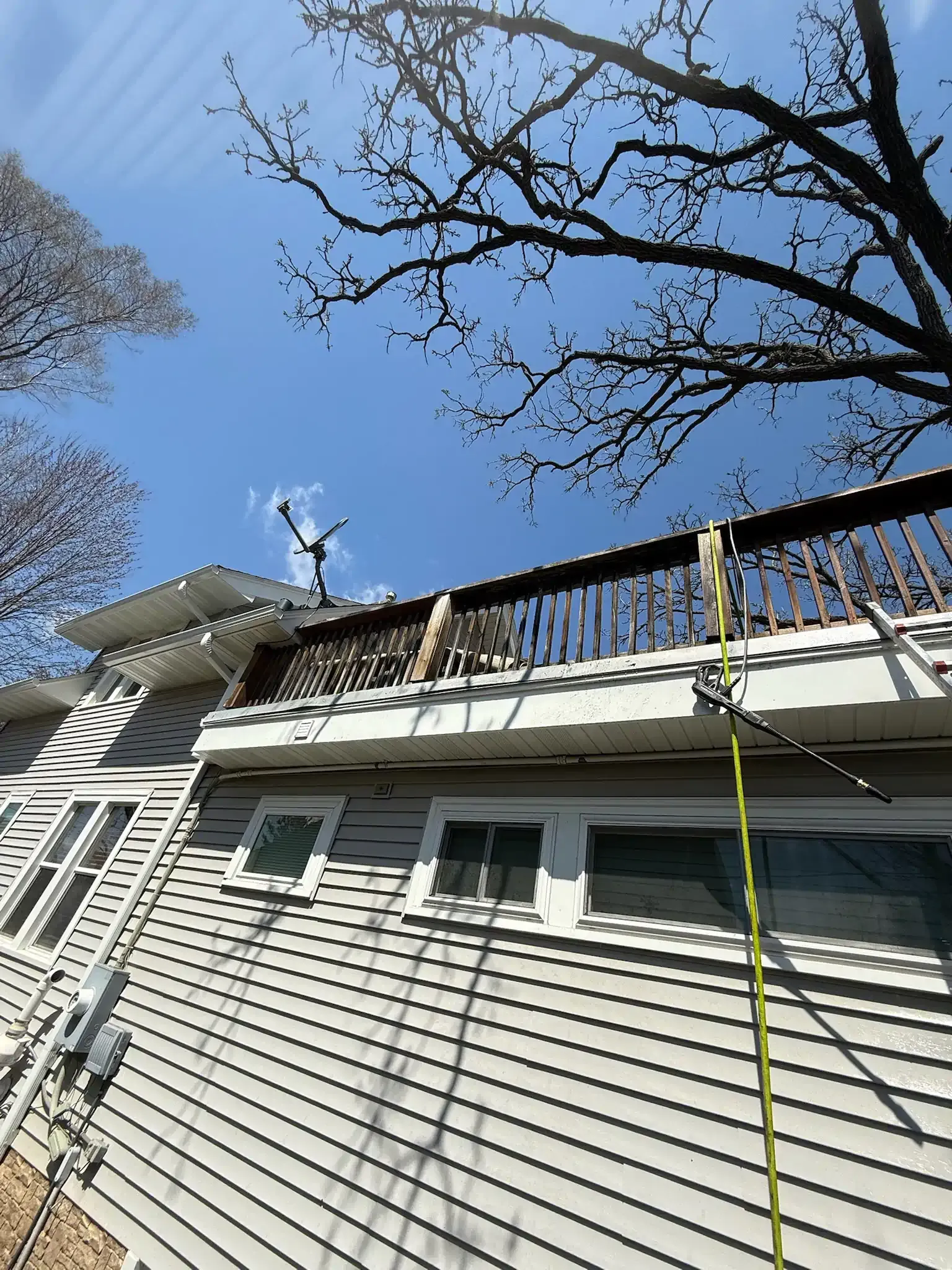 House exterior with a wooden deck, blue sky overhead.