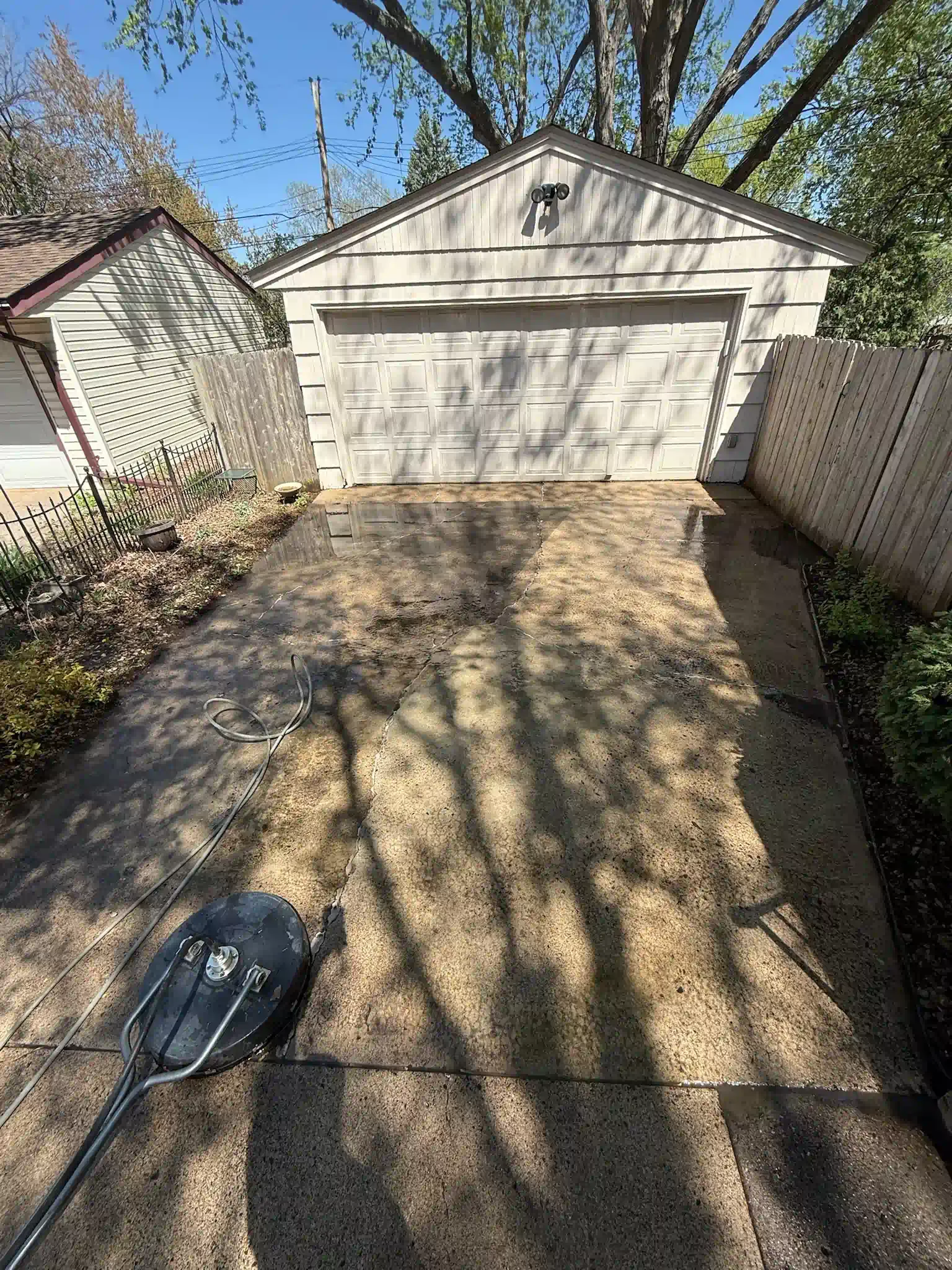 Concrete driveway leading to a garage; a shovel lies in the foreground.