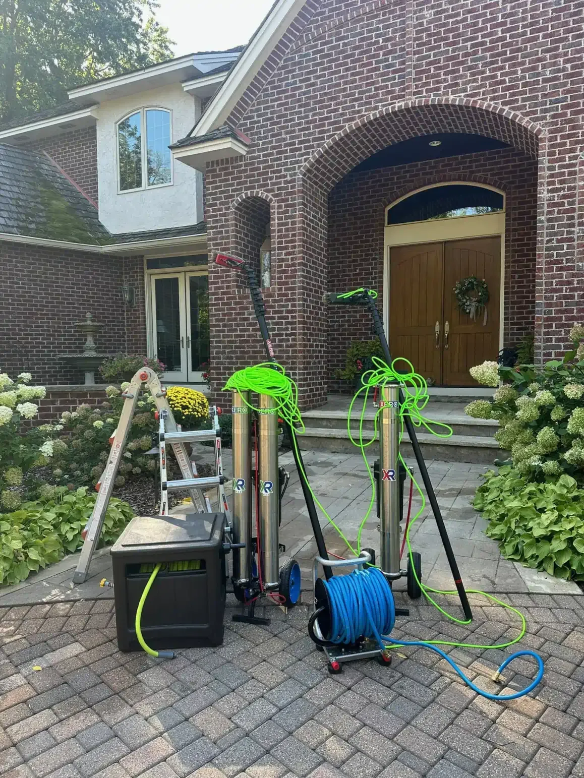 Window cleaning equipment set up in front of a brick house with a wooden door.