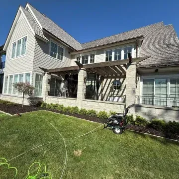 White house with large windows and a balcony, set against a cloudy blue sky.